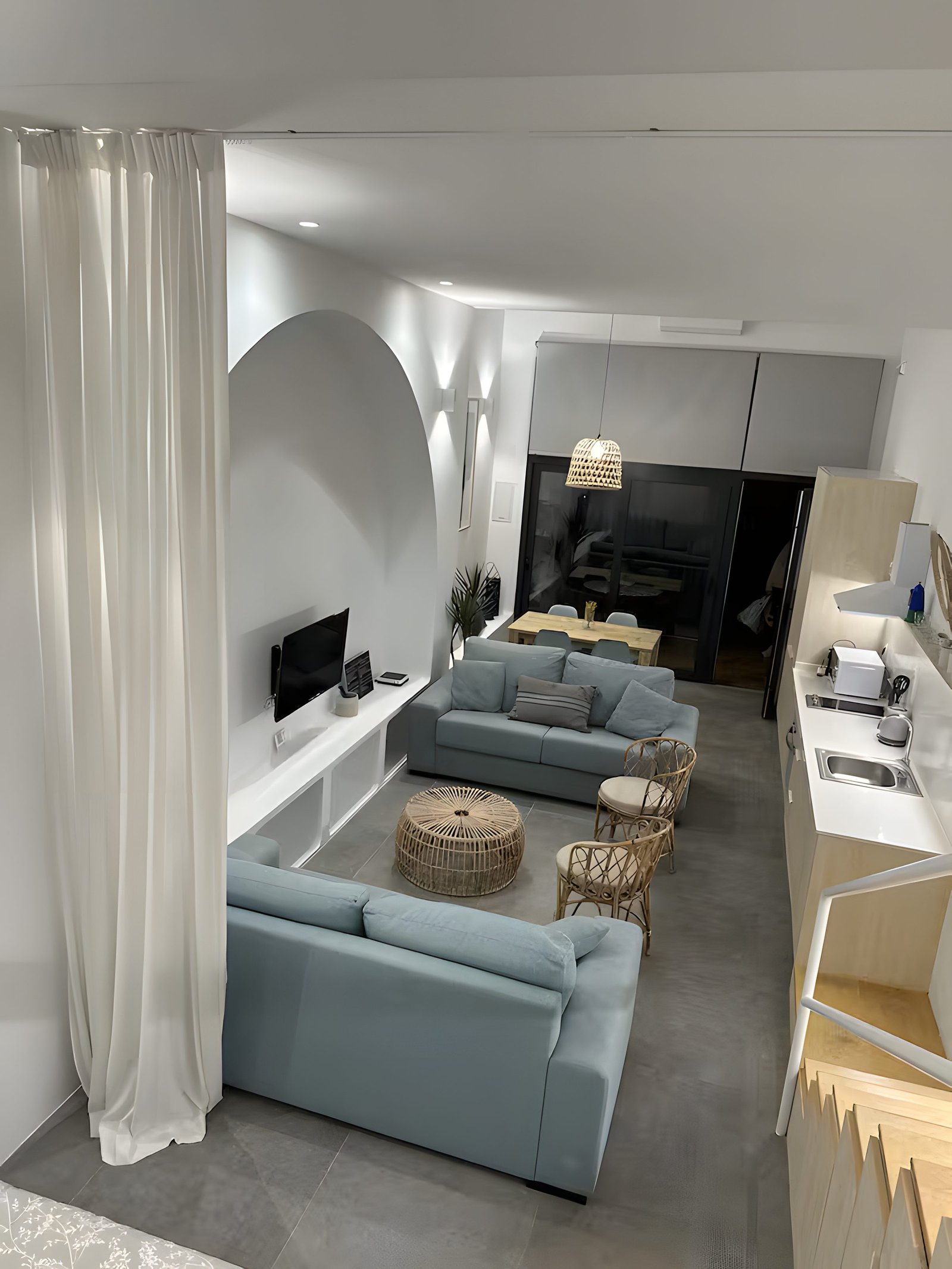 Vista elevada del loft con el salón y la cocina en tonos cálidos